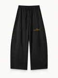NO NOISE Quiet Standard Wide-Leg Sweatpant — Black, front view showing drawstring waist, wide legs and gold artwork.