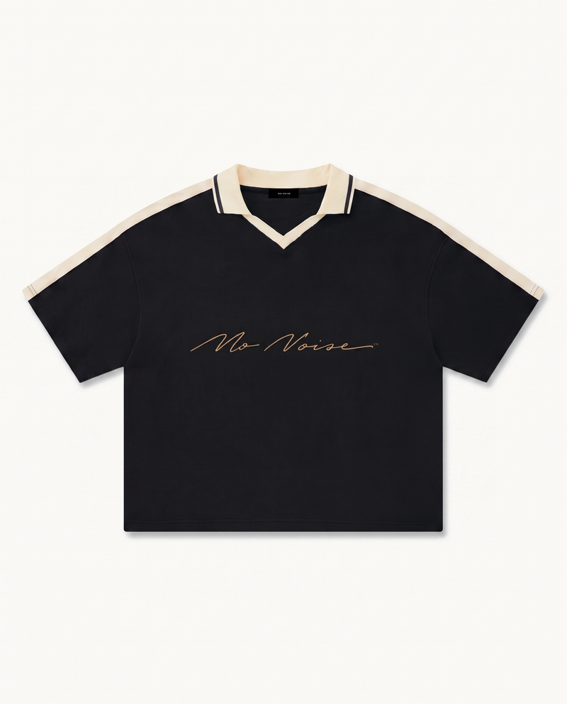 NO NOISE™ CHAPTER 001 PARIS UNISEX COLOR BLOCK POLO SHIRT — BLACK/CREAM — product view on warm ivory.