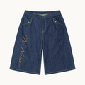 THE SANS BRUIT DENIM BERMUDA — INDIGO — product view on warm ivory.