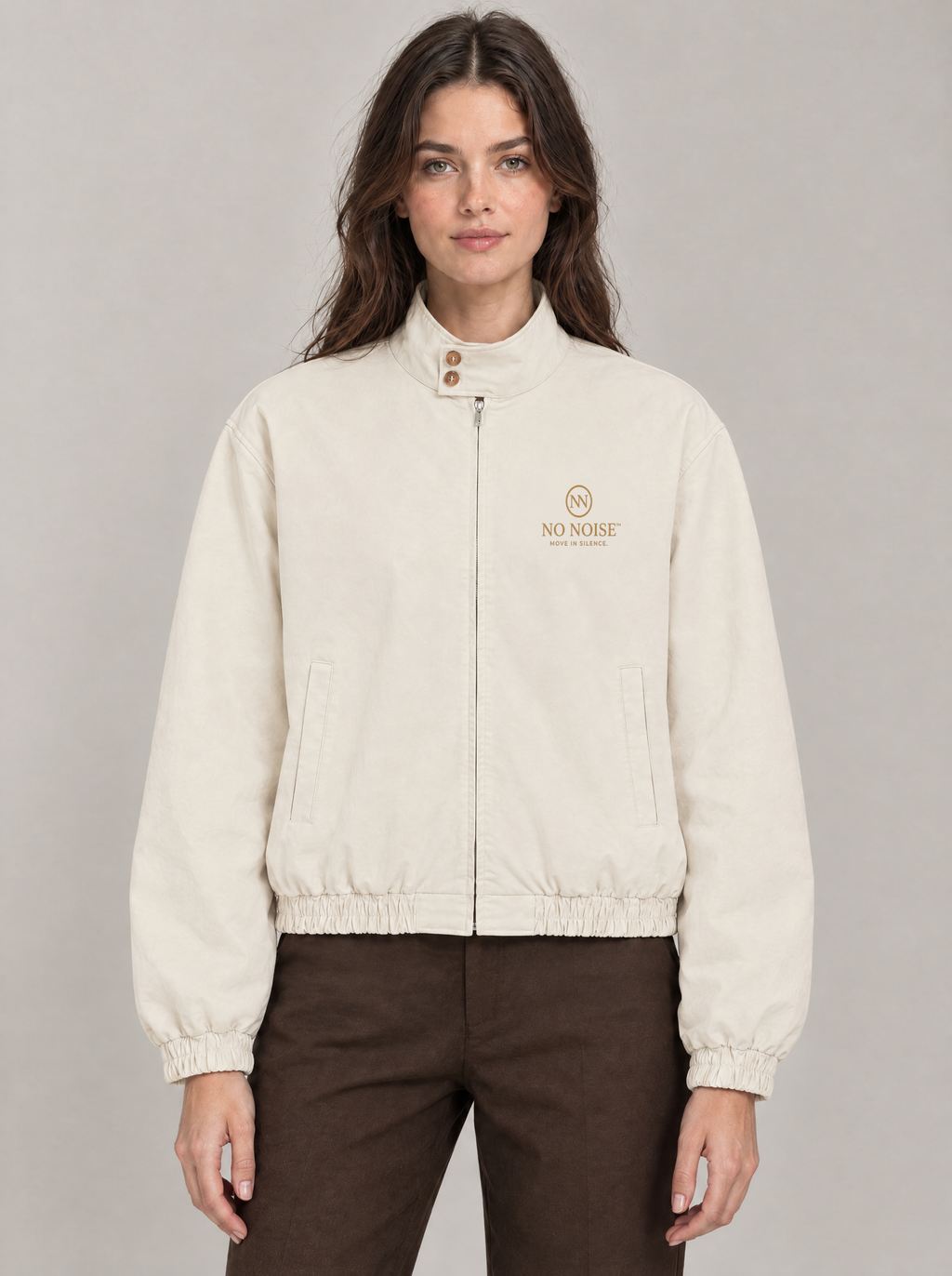 NO NOISE Silent Bomber in Cream, front model illustration showing two-button stand collar, zip closure, welt pockets and original gold chest artwork.