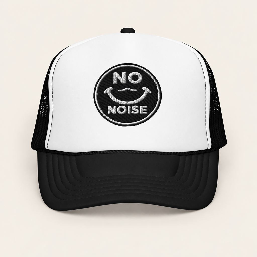 NO NOISE™ Quiet Signal Trucker Hat in black and white on a warm ivory background, front view.